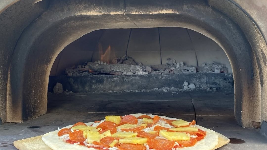 A pizza sliding into the glowing wood-fired oven